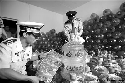城管和工商人员正在清点现场的假冒桶装水。本报通讯员姚震摄