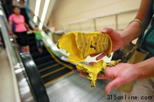 昨日下午,刘女士在出事扶梯前展示儿子被夹坏的凉鞋。本报记者 王贵彬 摄
