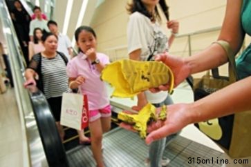 刘女士在出事扶梯前展示儿子被夹坏的凉鞋。记者 王贵彬 摄