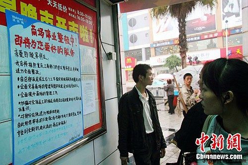 10月11日,重庆市民在万州沃尔玛太白路分店超市门口关注停业整顿公告。近日,因涉销售假冒“绿色猪肉”,沃尔玛在渝13家门店被当地工商部门责令停业整顿15天。中新社发 赵俊超 摄