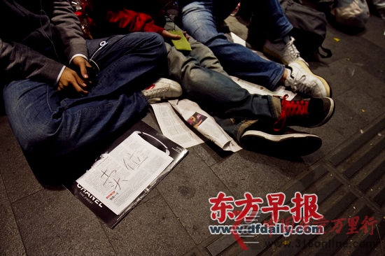 昨晚,淮海路H&M专卖店门外,一名排队的小伙在前面放着个牌子——“卖位”。